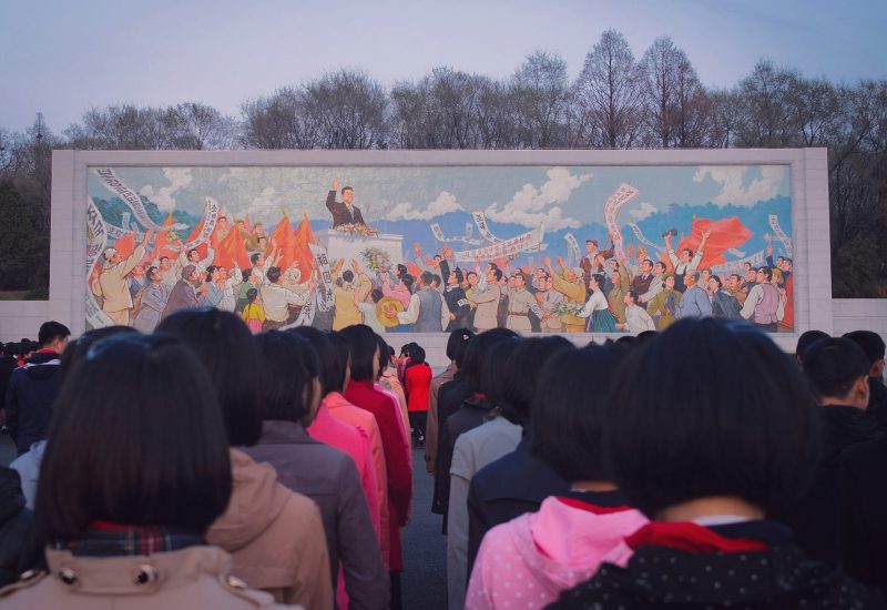 Children line up in front of a mural in Pyongyang, North Korea
